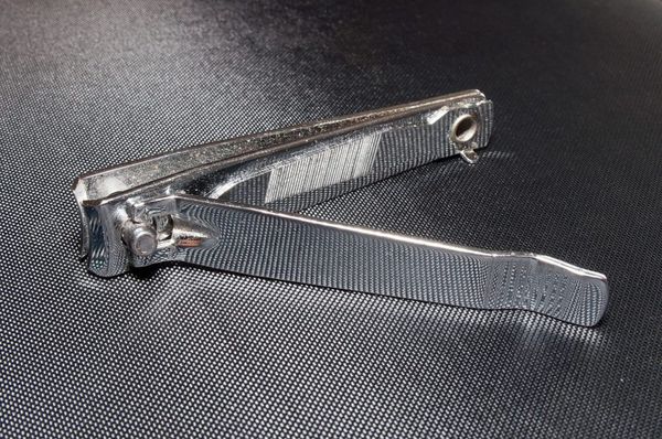 A close up of a nail clipper. Black textured background.